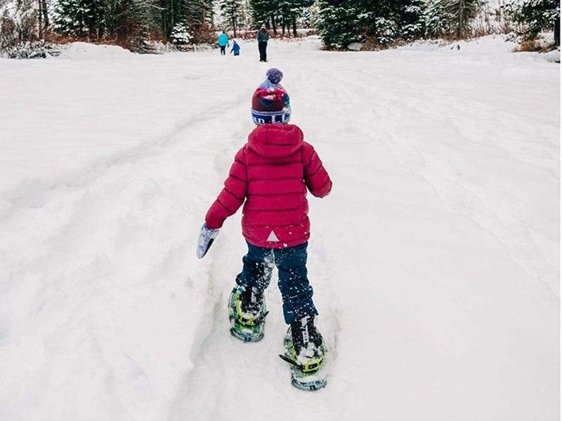 The Bowman family snowshoeing across a wintry field.