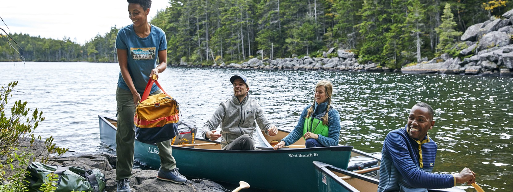 Four friends around a dock, gearing up for canoe camping.