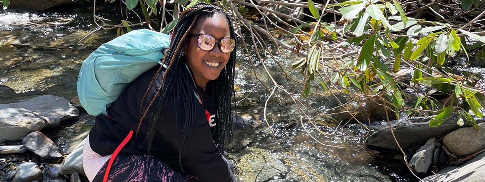 Nicole R. bending down by a stream.