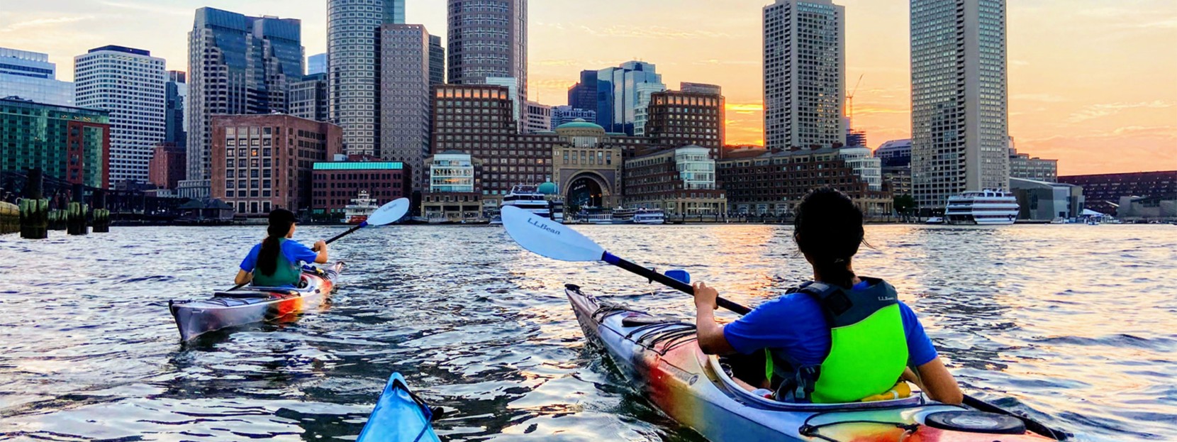Two kayakers headed into Boston Harbor at sunset.