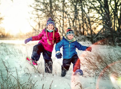 2 happy kids snowshoeing in a field.