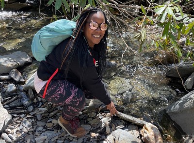 Nicole R. bending by a stream.