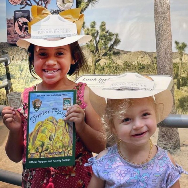 Two children smiling with their Junior Ranger badge and activity book