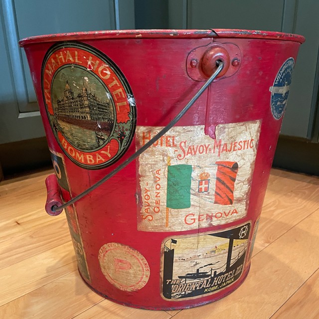 Antique red pail decorated with momentos from an international trip.