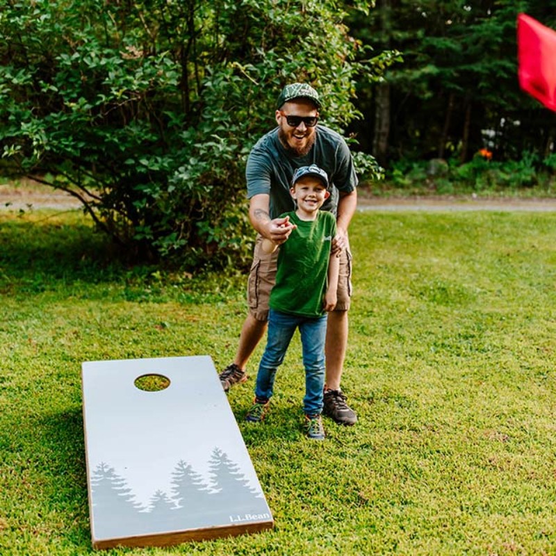 A father and son outside playing cornhole.