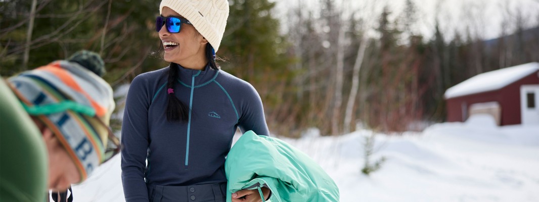 Two people outside in winter, one holding a jacket and wearing a base layer.