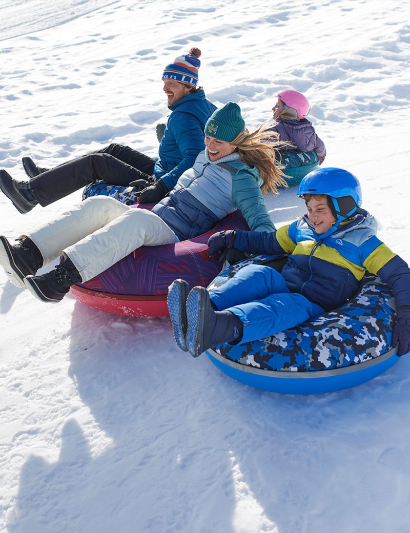 A family of 4 sliding down a hillside on L.L.Bean Sonic Snow Tubes.