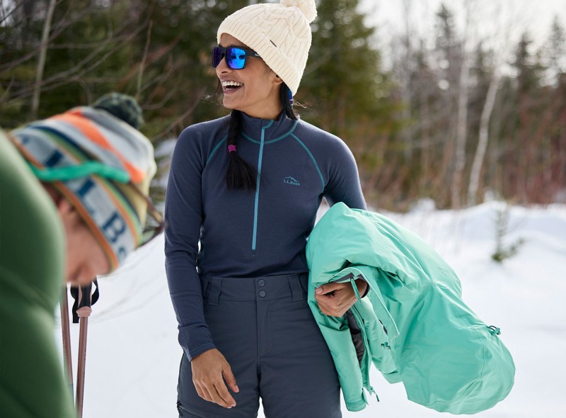 Two people outside in winter, one holding a jacket and wearing a base layer.