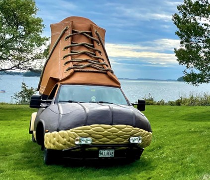 The Bootmobile, parked in a green field with the ocean in the background.