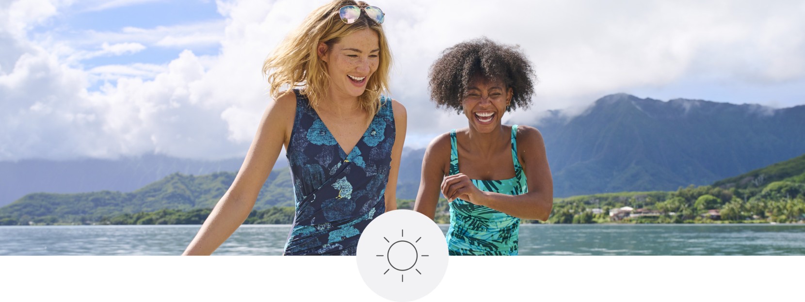 2 women in bathing suits walking by the water on a beautiful summer day.