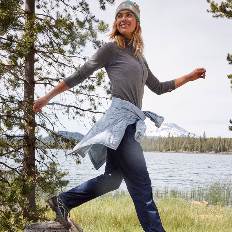 A woman outside hiking, a jacket tied around her waist.