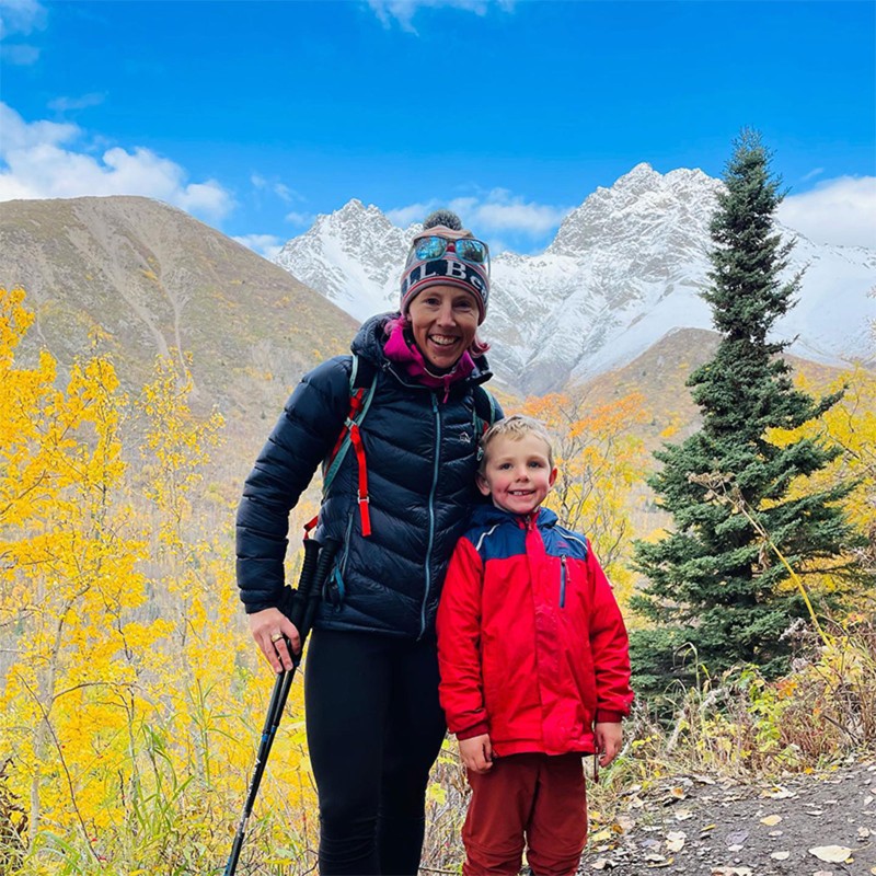 Kikkan Randall and her son on a fall hike, snow-covered peaks in the distance.