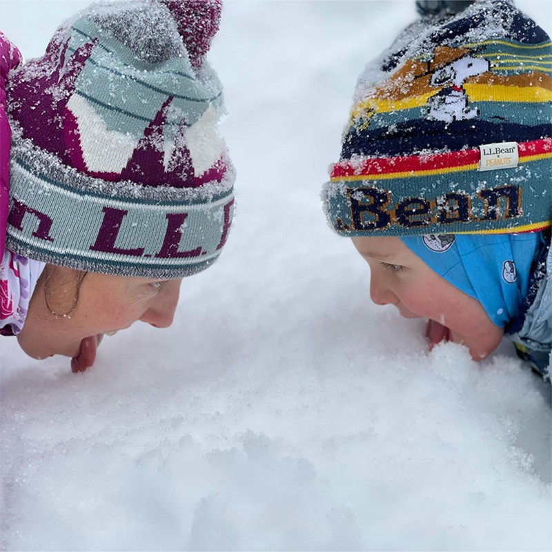 A close-up of Kikkan Randall and her young son looking at each other while sticking their tongues in freshly fallen snow.
