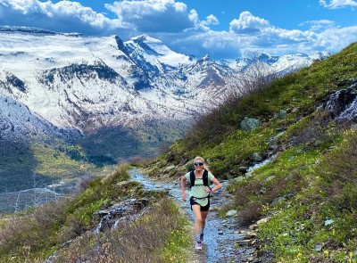 Jessie Diggins trail running, snow-covered mountains in the background.