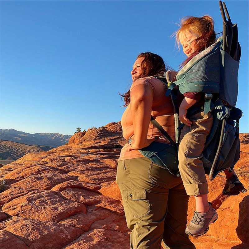 L.L.Bean Ambassador Melody Forsyth standing on a trail enjoying the view, her daughter in a child carrier on her back.