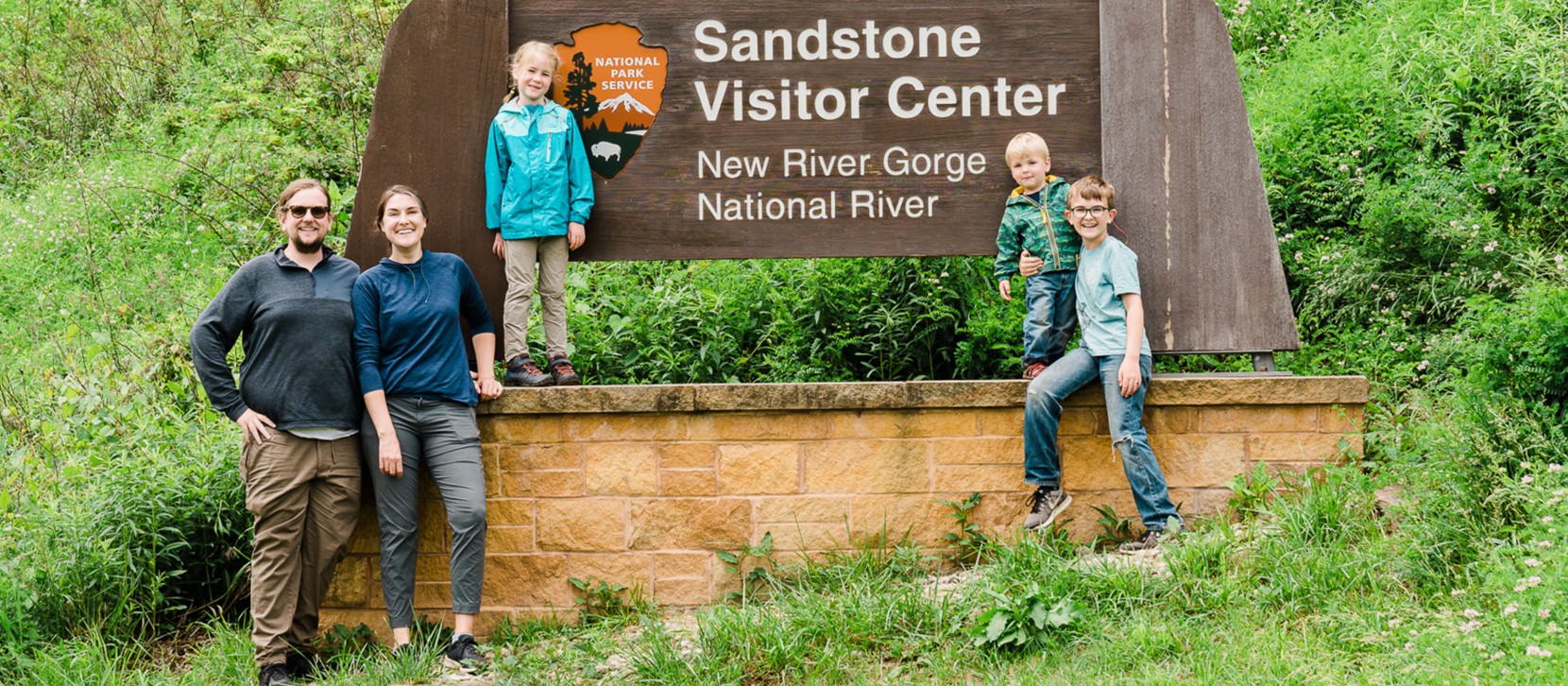The Bowman family standing on and around the Sandstone Visitor Center sign.