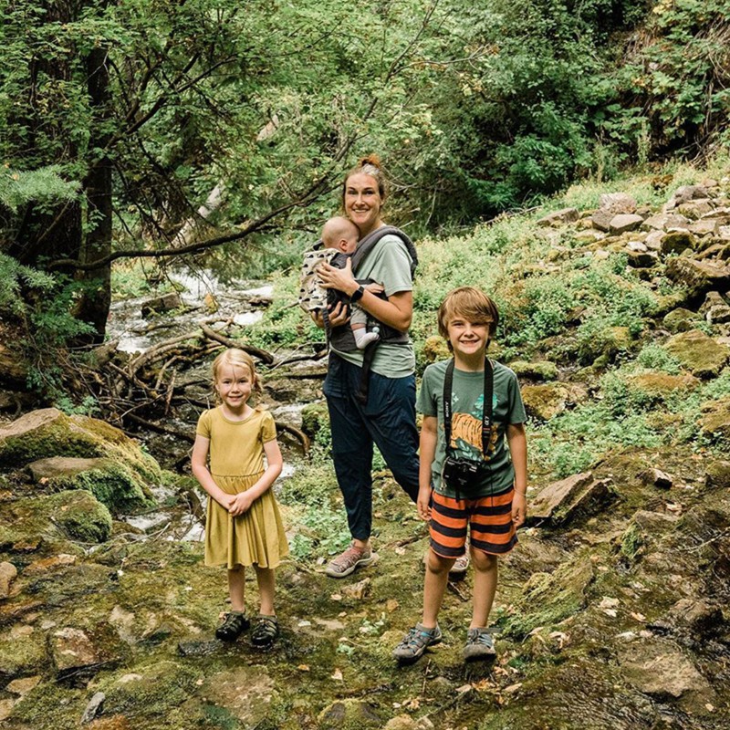 Madison Bowman and her 3 kids smile for the camera on a mountain trail.