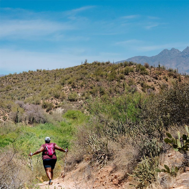 L.L.Bean Ambassador Mirna Valerio walking on a high desert trail, mountains in the distance.