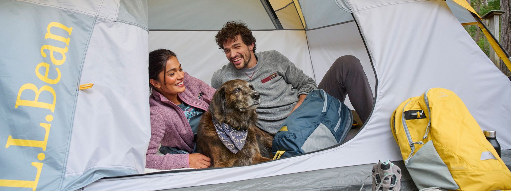 A close-up of a couple and a dog in a tent.