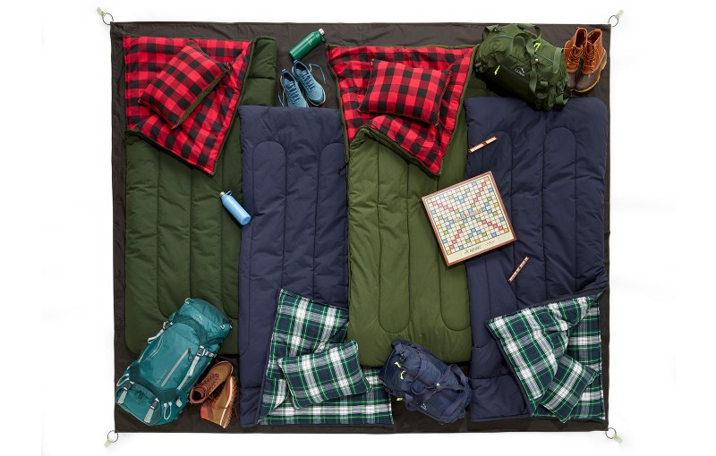 An overhead shot of 4 sleeping bags arranged on a 6-person tent footprint, all extra gear inside the footprint.
