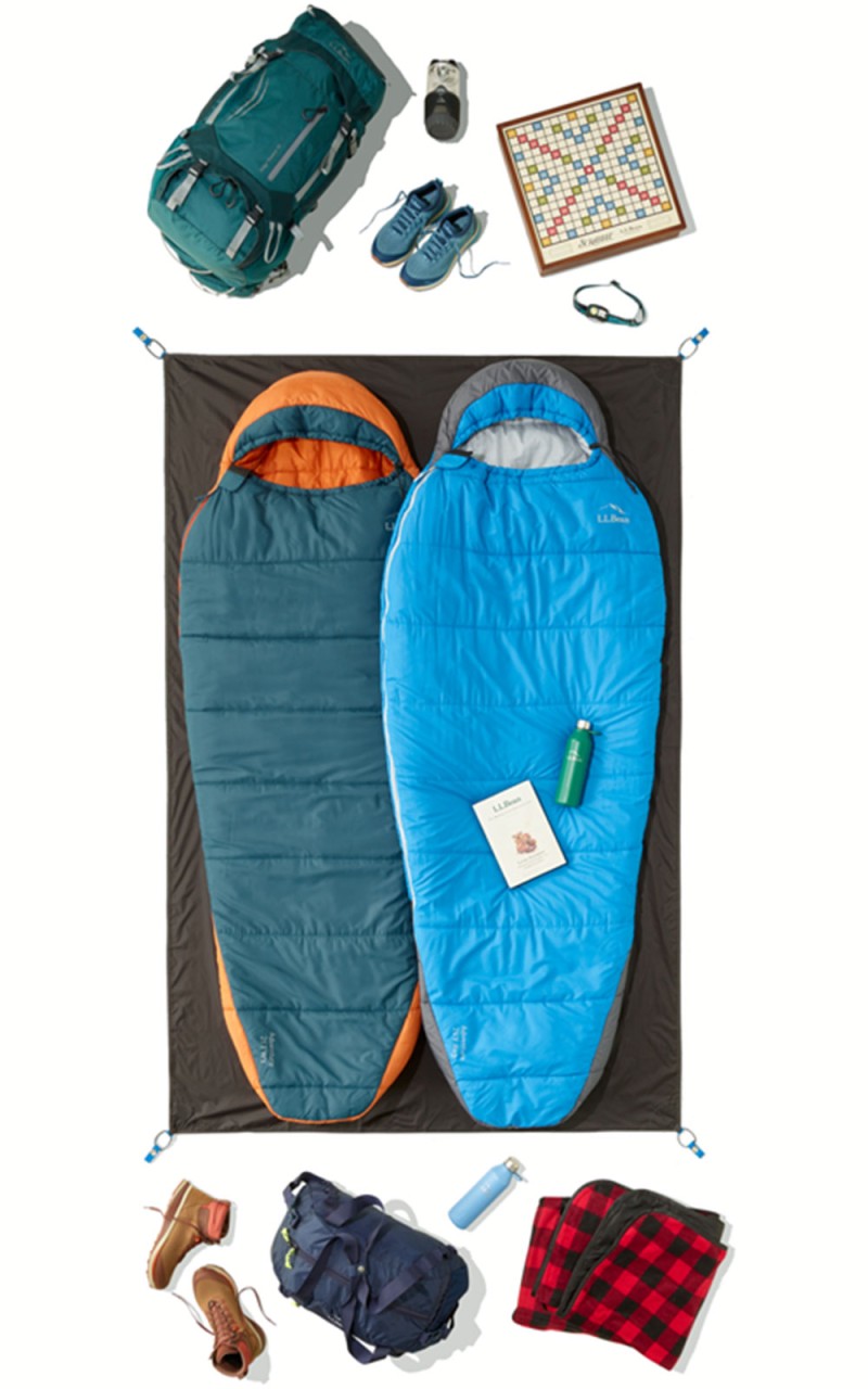 An overhead shot of 2 sleeping bags arranged on a 2-person tent footprint, all extra gear outside the footprint.