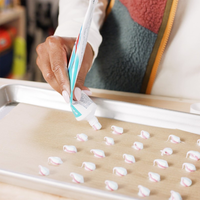 Stephanie squeezing dots of toothpaste onto parchment paper.