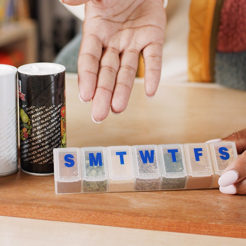 Stephanie showing a pill organizer filled with different spices.