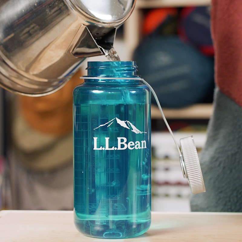 Stephanie filling a water bottle with hot water from a camp kettle.