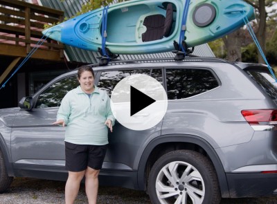 MacKenzie standing by a car with a kayak on top.