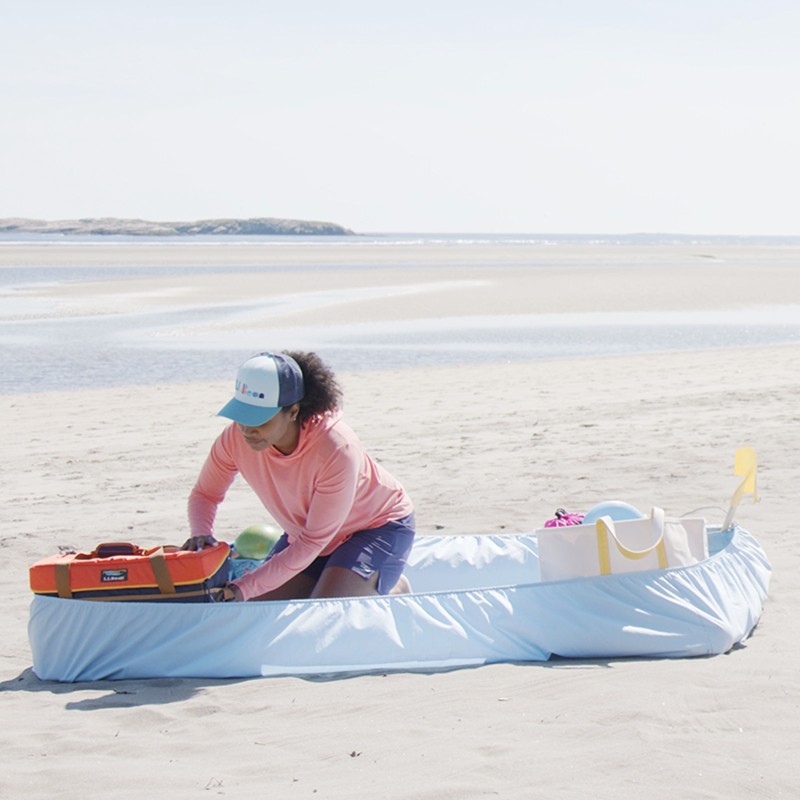 Stephanie organizing her beach gear in/on a fitted sheet on the sand.