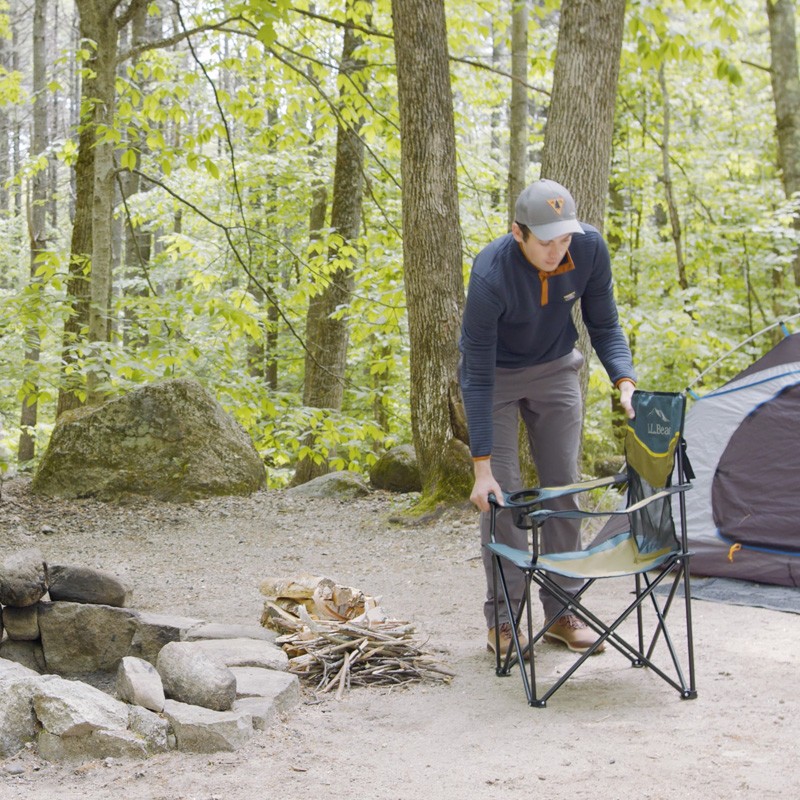 Nate setting up a camp chair in front of a fire ring at a campsite.