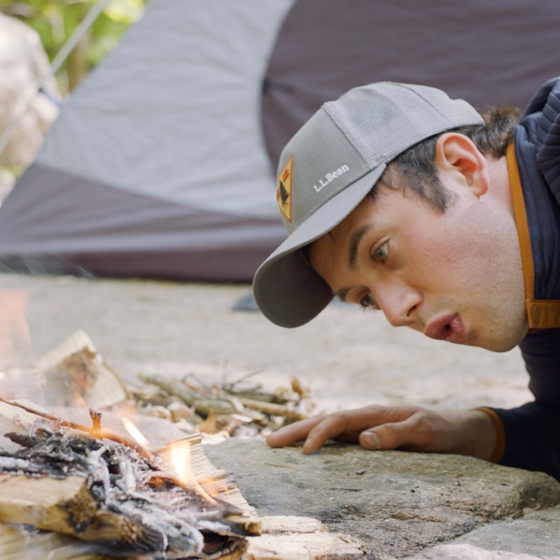 Nate blowing gently on the base of a fire.