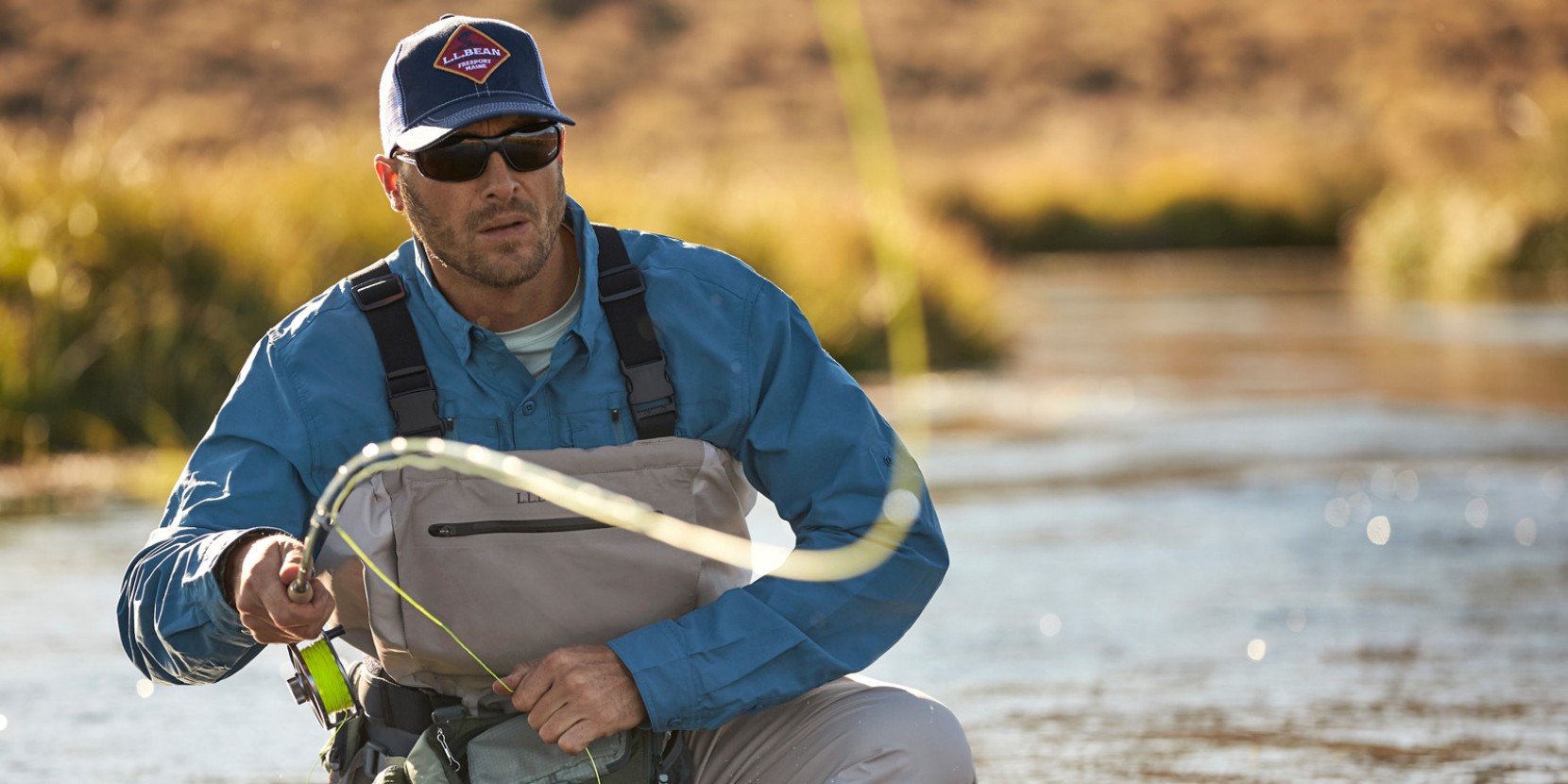 A man in waders fly-fishing in a river.