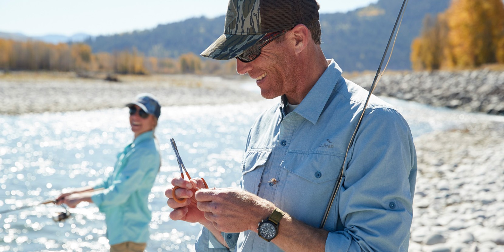 A smiling man and woman fly-fishing wearing bug repelling shirts.