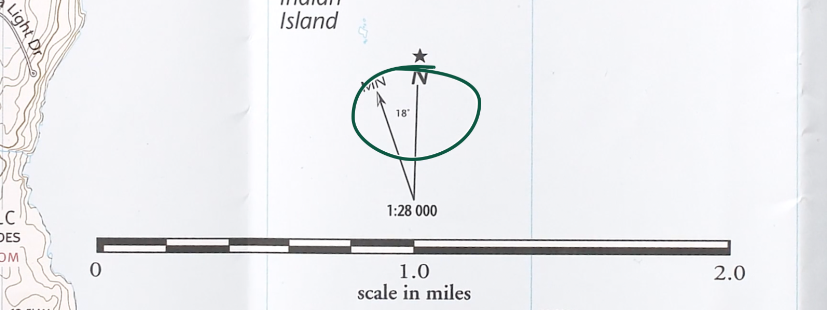 A close-up of a map's declination diagram with a green circle around the angle between true north and magnetic north.