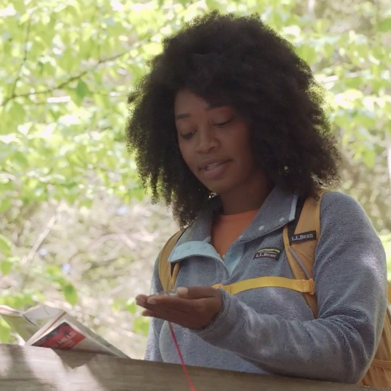 Stephanie outside looking at a compass in one hand and holding a map in the other.