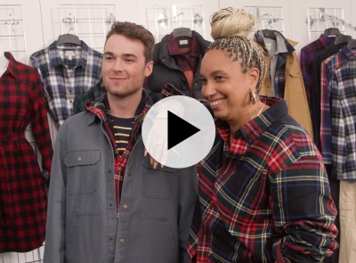 A model dressed in flannel stands with his stylist.