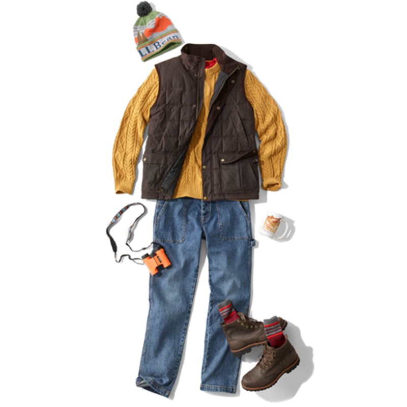 A laydown of an outfit featuring a quilted vest over a sweater, propped with binoculars and a mug.