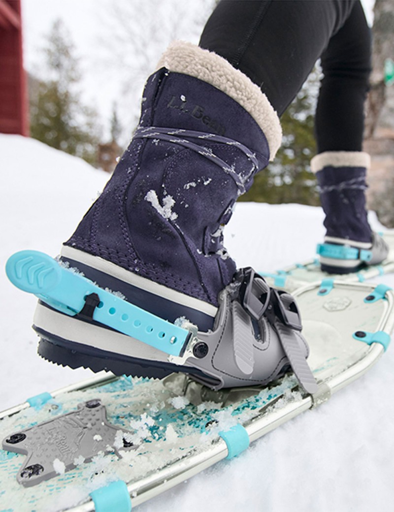 Close-up of boots and snowshoes on feet, walking on the snow.