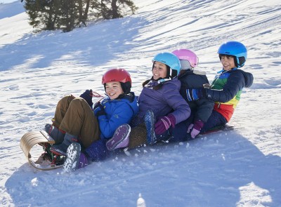 Four kids sledding on a toboggan