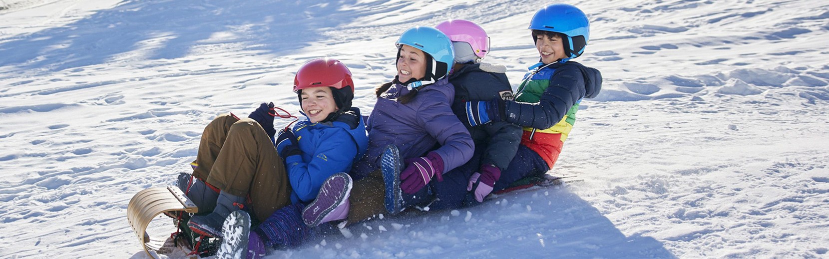 Four kids sledding on snow tubes