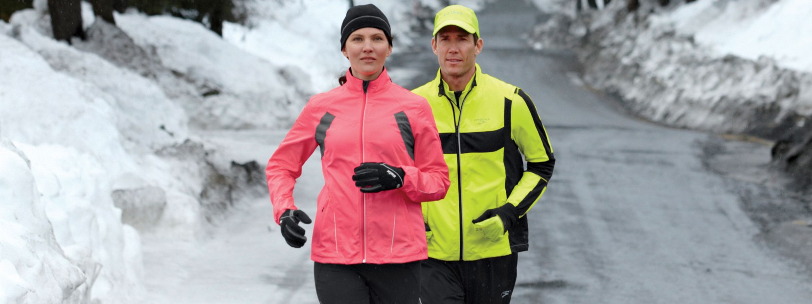 A man and a woman running on a snow covered road