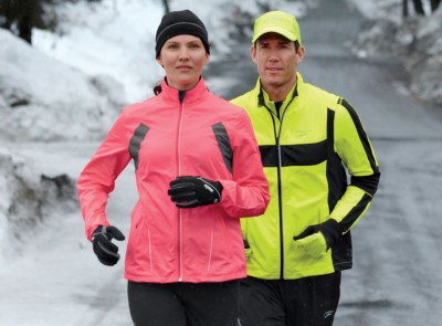 A man and a woman running on a snow-covered road.