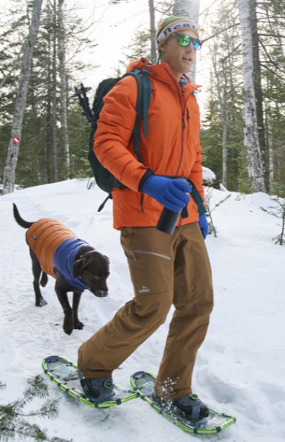 Man snowshoing on a winter trail with his dog