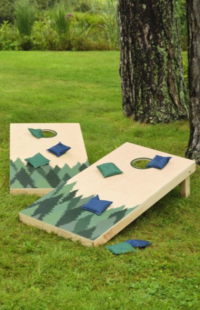 Image of two cornhole boards with beanbags all sitting on green grass.
