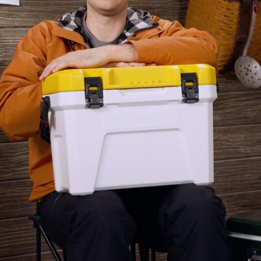 Close-up of a seated person with a closed bait bucket on their lap.
