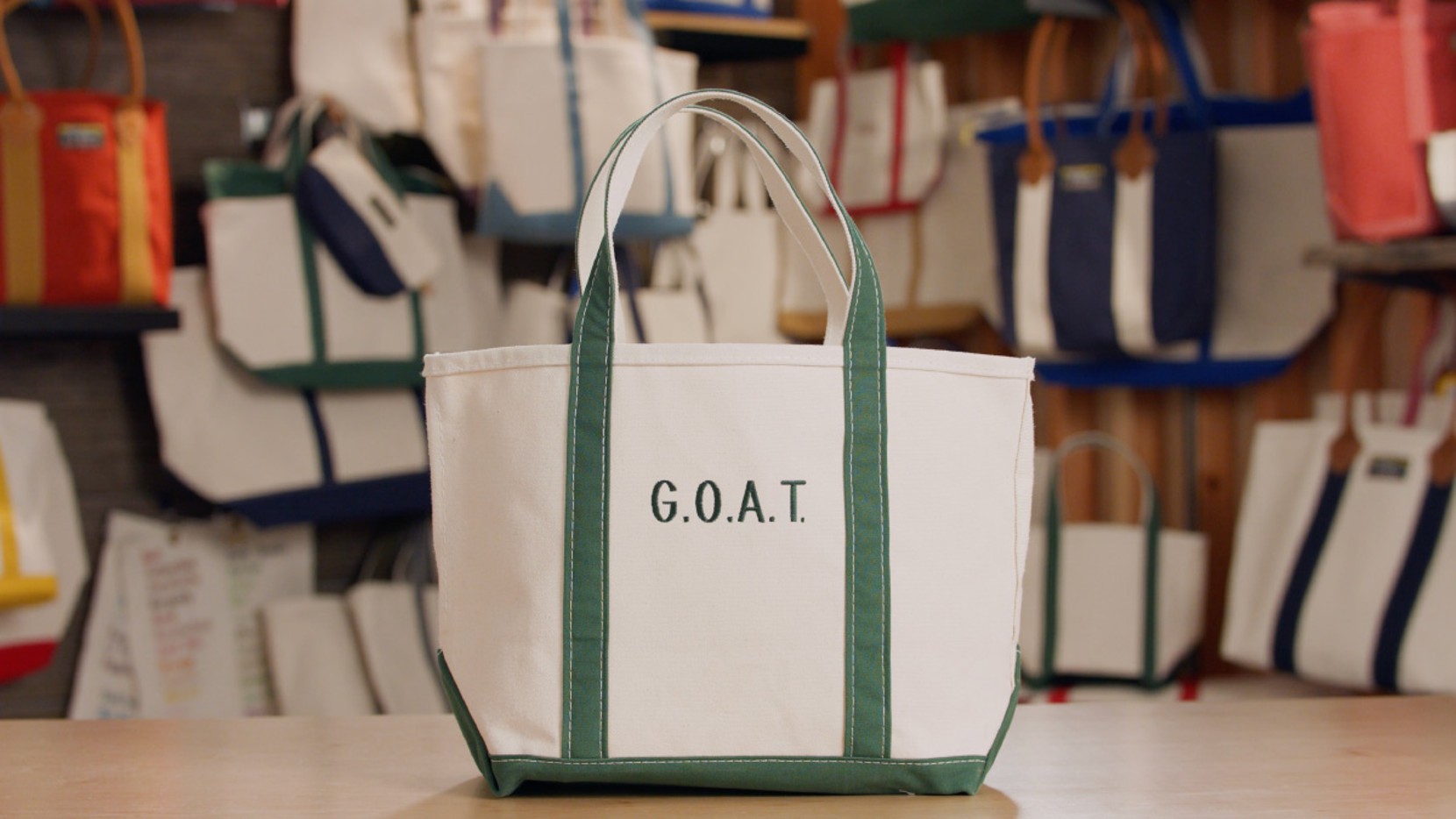 A Boat & Tote with green handles and a green monogram - "G.O.A.T."