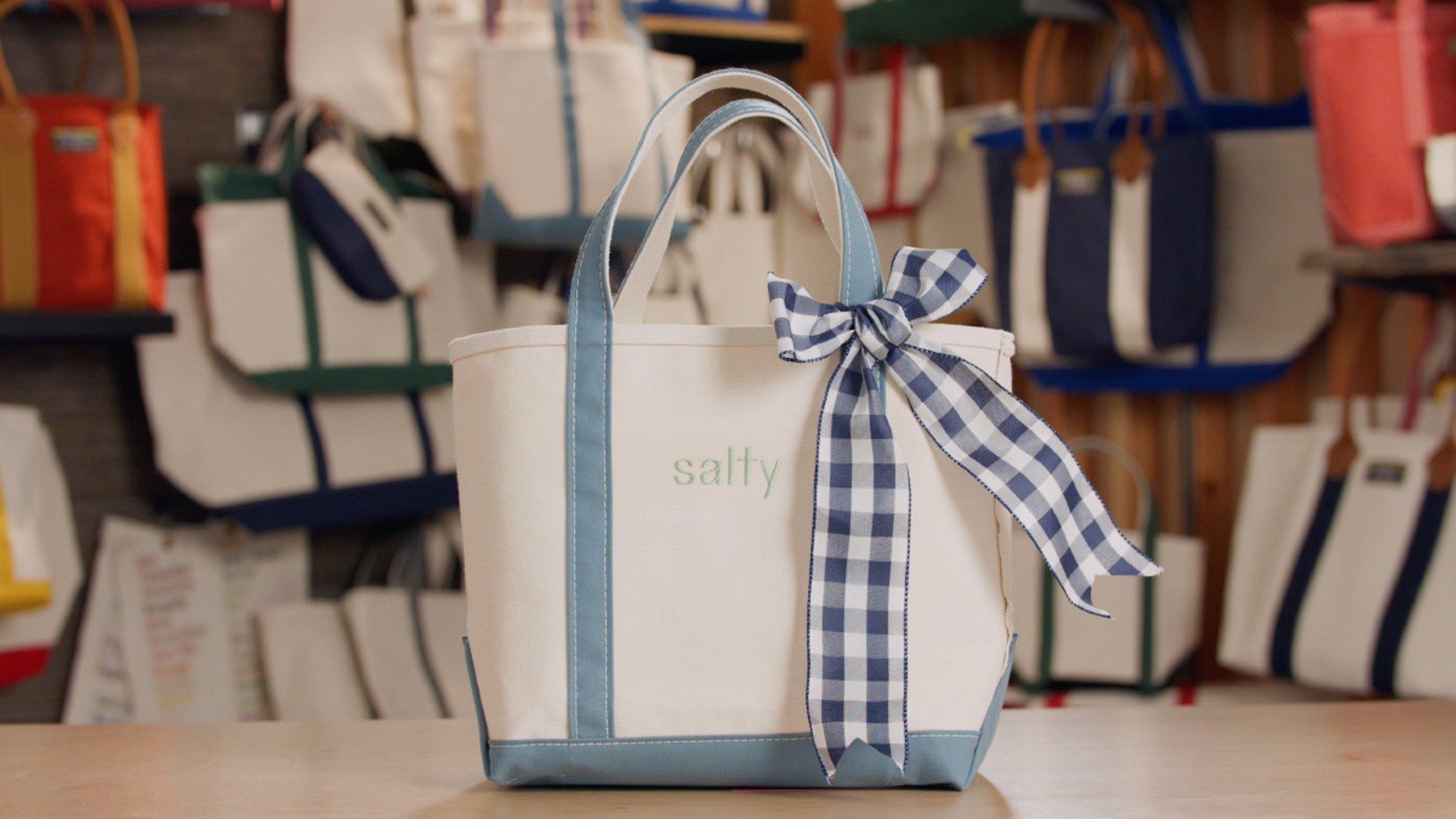 A Boat & Tote with light blue handles and a light blue monogram - "salty", a navy gingham bow tied on the handle.