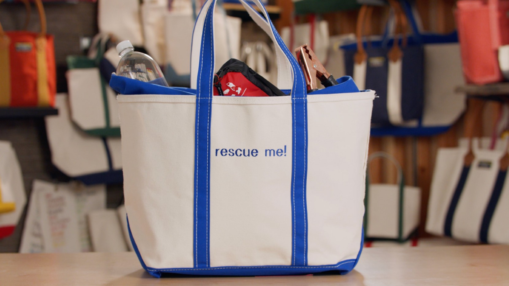 A large Boat & Tote with royal blue handles and monogram - "rescue me!", filled with emergency items for the car.