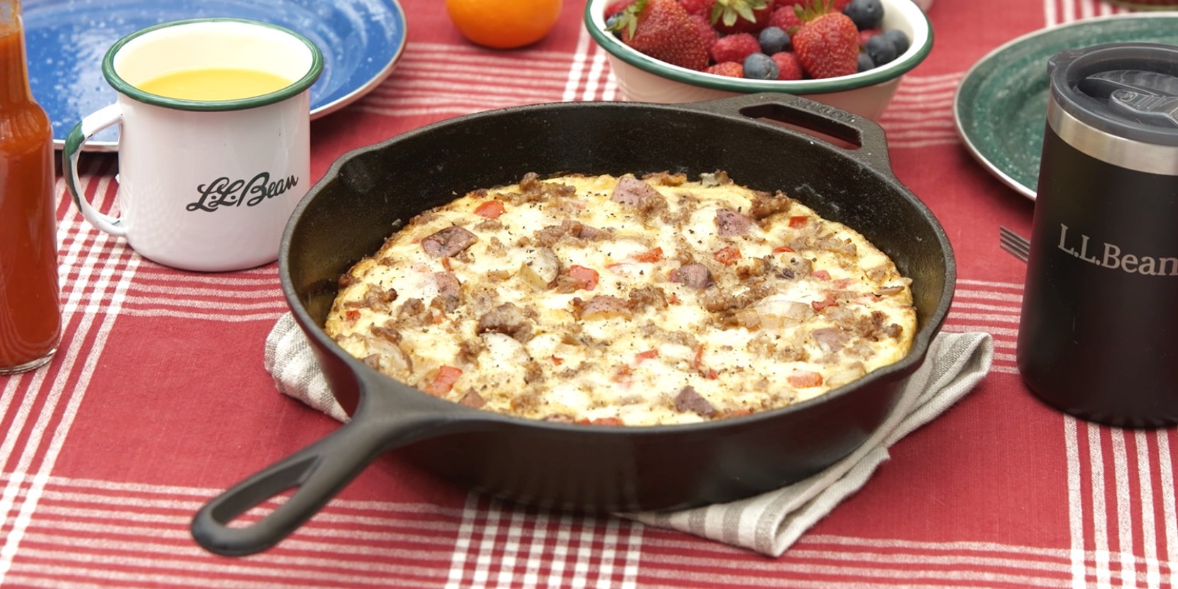 A frittata in a cast iron skillet sits on a picnic table.